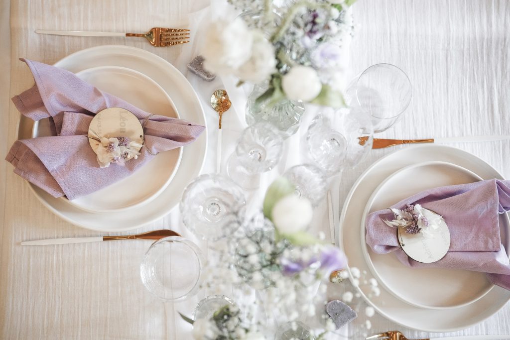 Table dressée avec vaisselle, verres et fleurs mauves, illustrant la location de matériel événementiel en Provence.